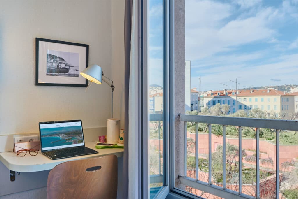 Espace de travail avec vue sur Nice depuis fenêtre.
