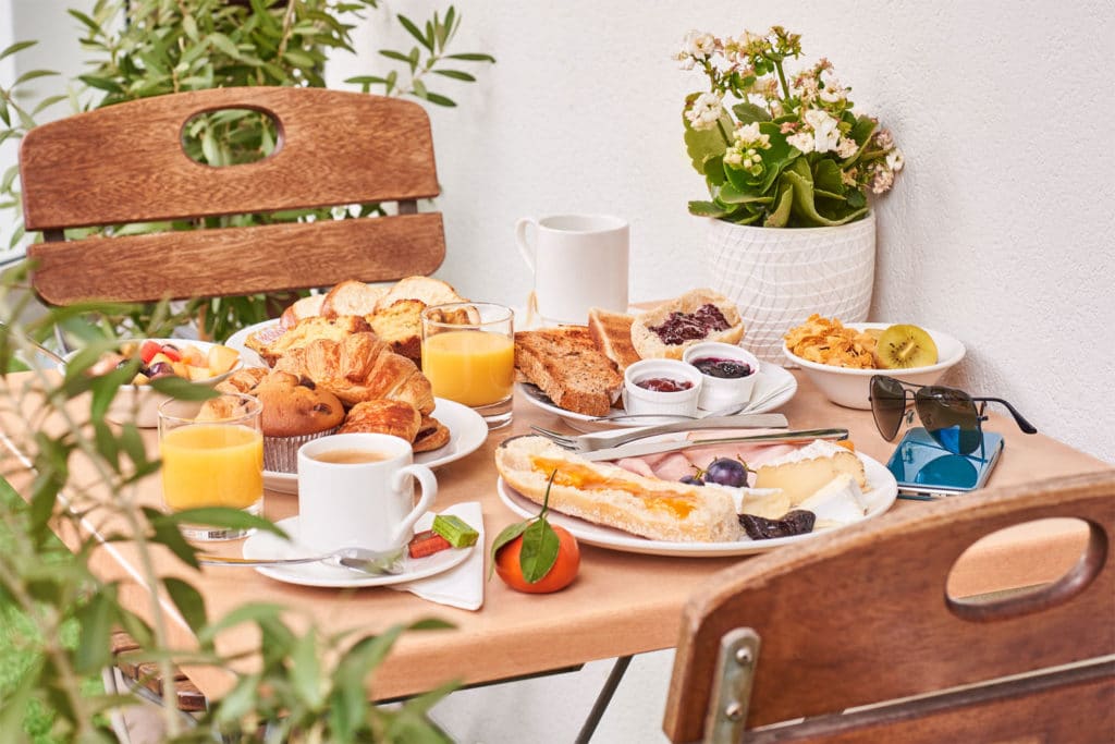 Petit déjeuner varié sur table extérieure avec viennoiseries.