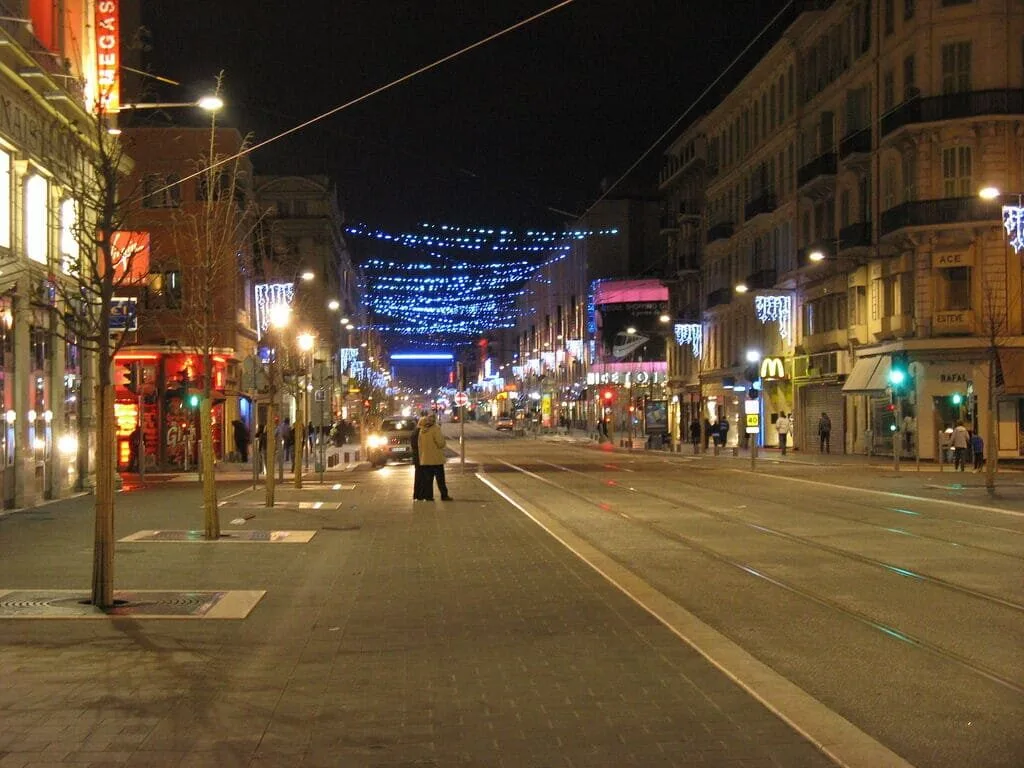 Rue illuminée à la nuit avec tramways.