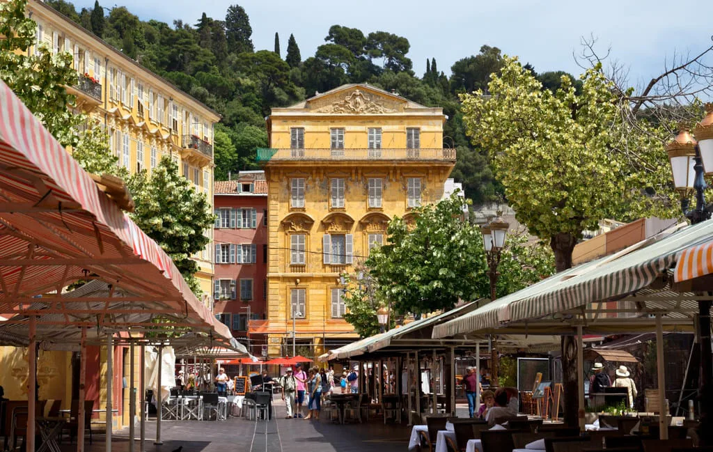 Place avec bâtiments colorés et marché, ciel bleu.